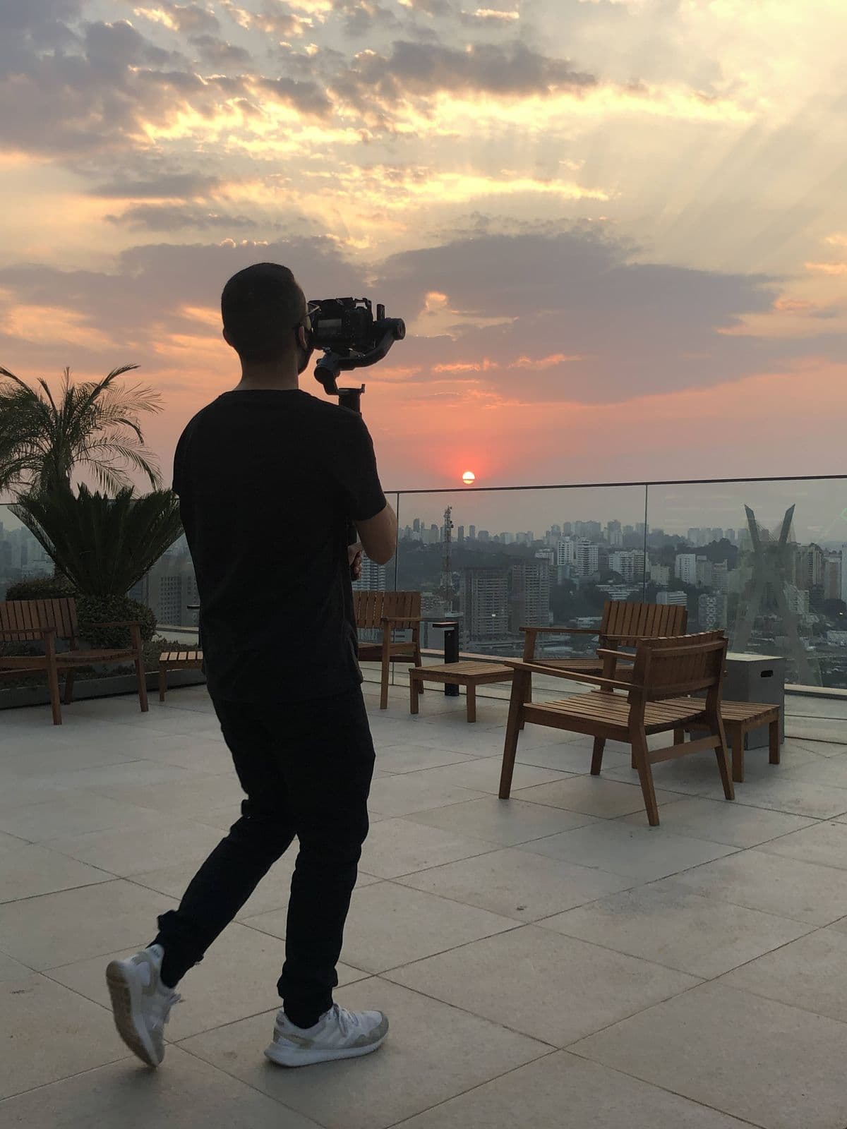 Nando from behind, filming the sunset on a rooftop