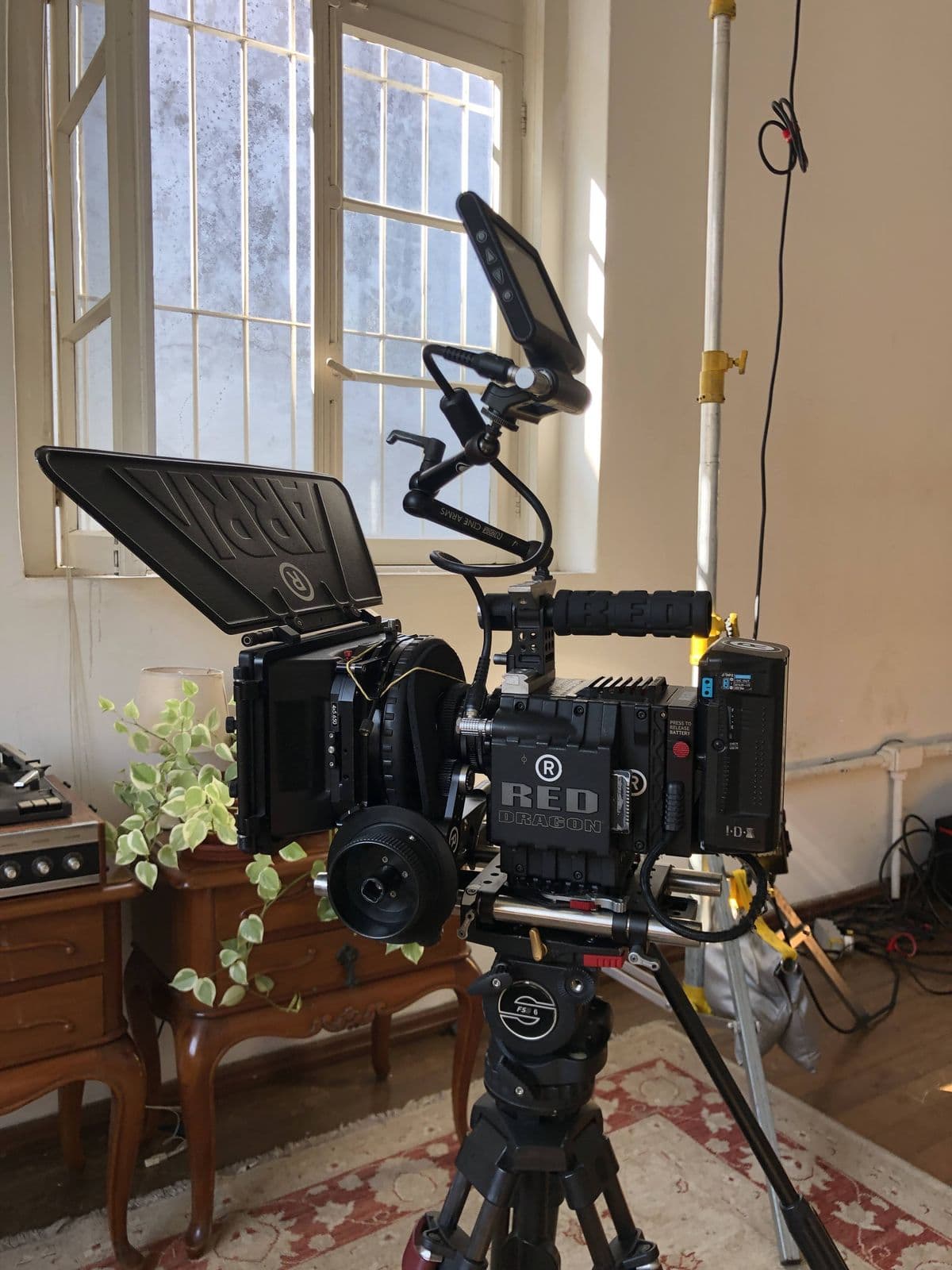 Cinema camera on a tripod, in a room with tall windows and antique furniture
