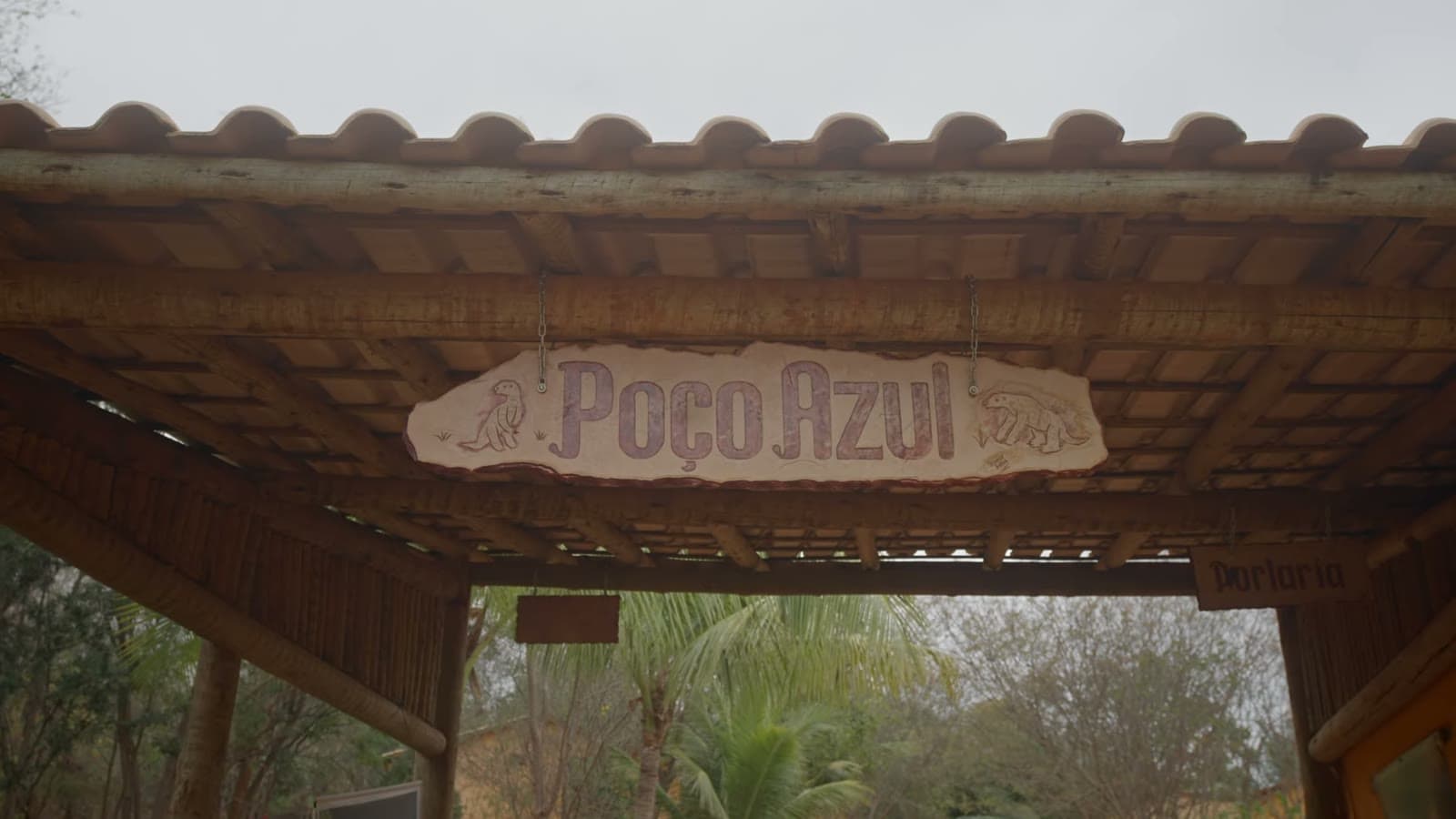 Placa de madeira escrita Poço Azul, pendurada sob o telhado da portaria do parque