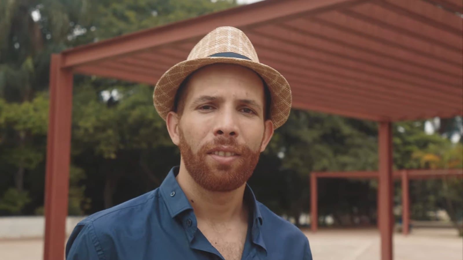 Retrato de un hombre de sombrero bajo una pérgola roja