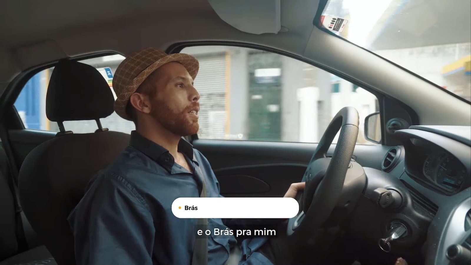 Un hombre con sombrero manejando, con un globo blanco que dice Brás