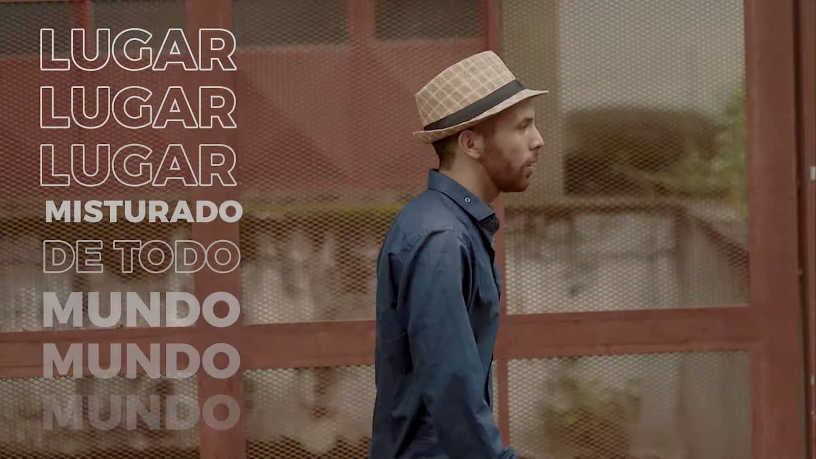Un hombre con sombrero camina frente a un portón rojo; al lado, las palabras “lugar mezclado de todo el mundo” repetidas