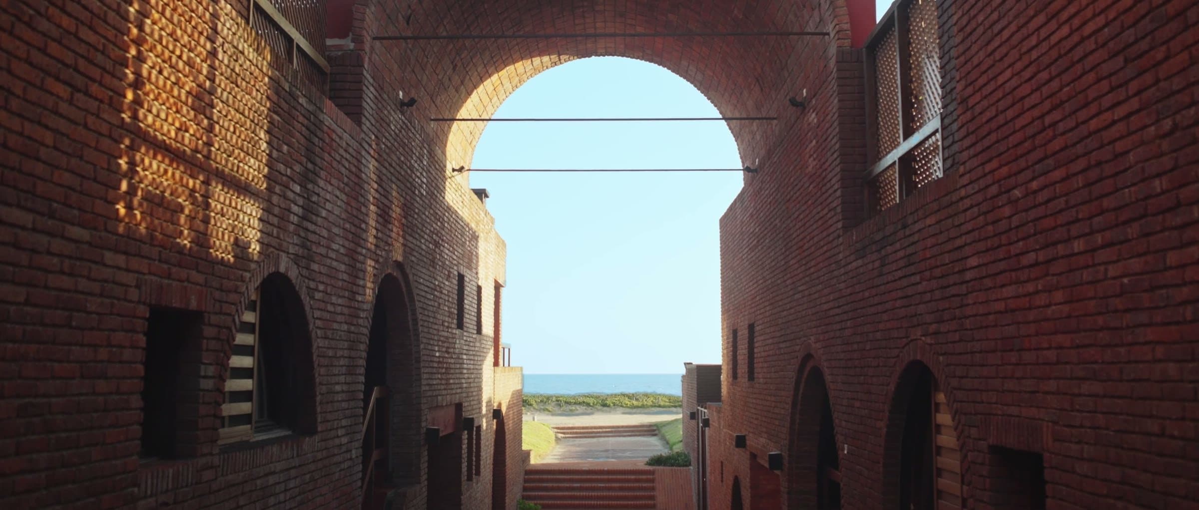 A brick corridor opening onto the sea