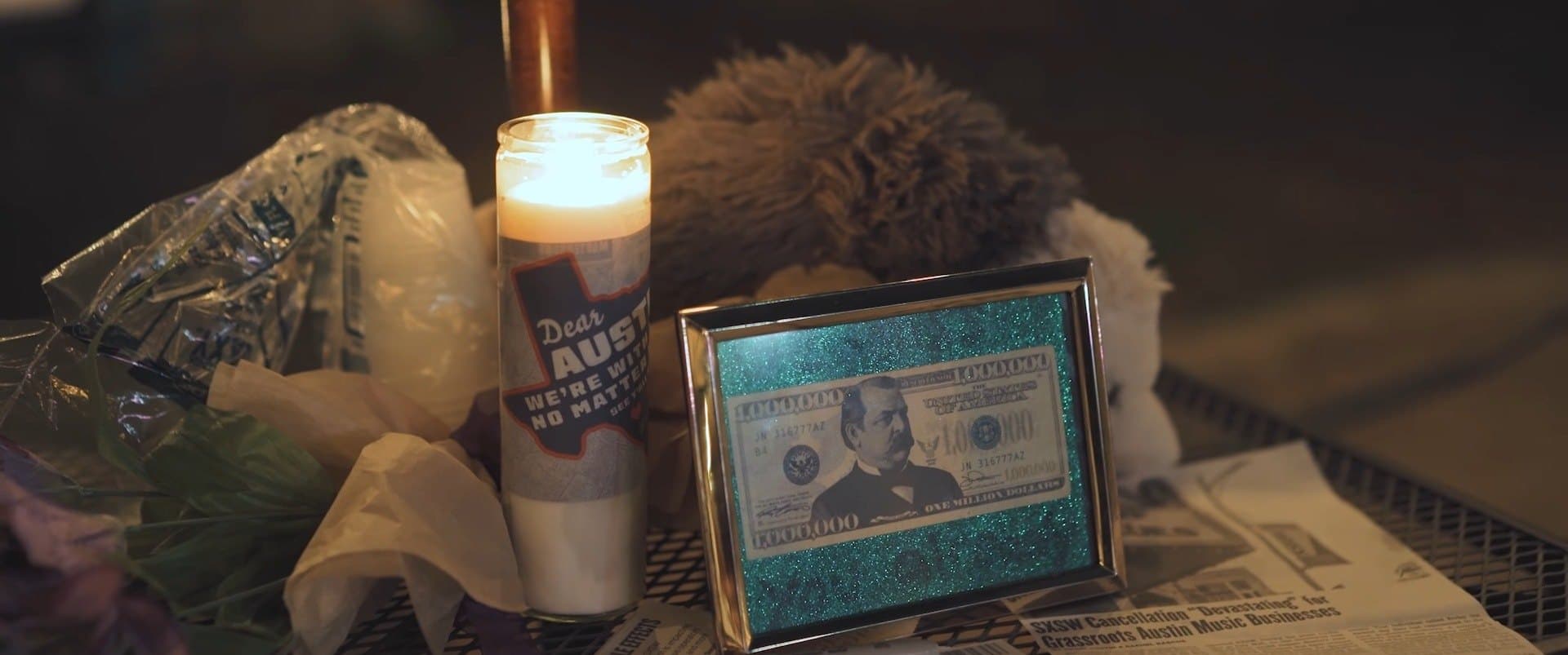 A lit candle before a framed dollar bill