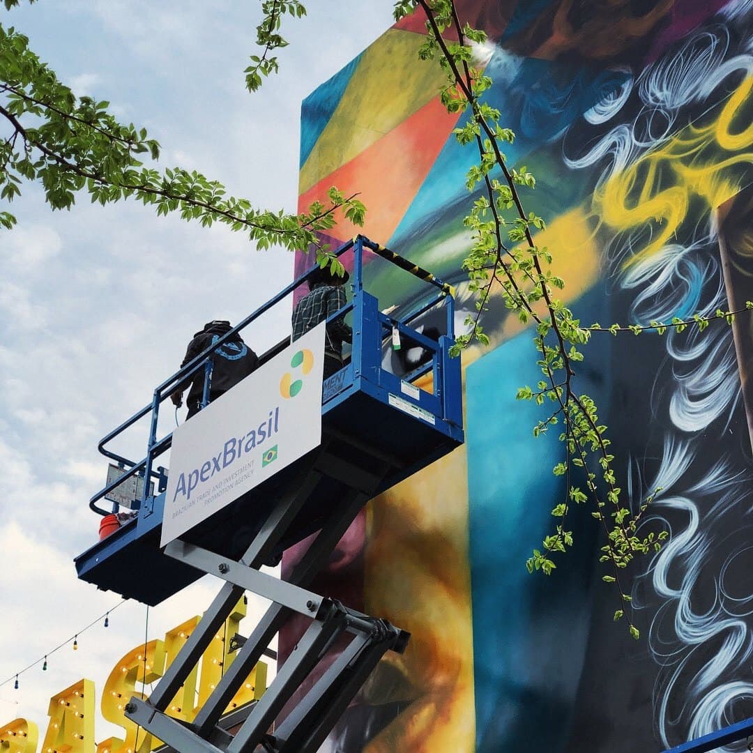 The mural being painted from an ApexBrasil platform