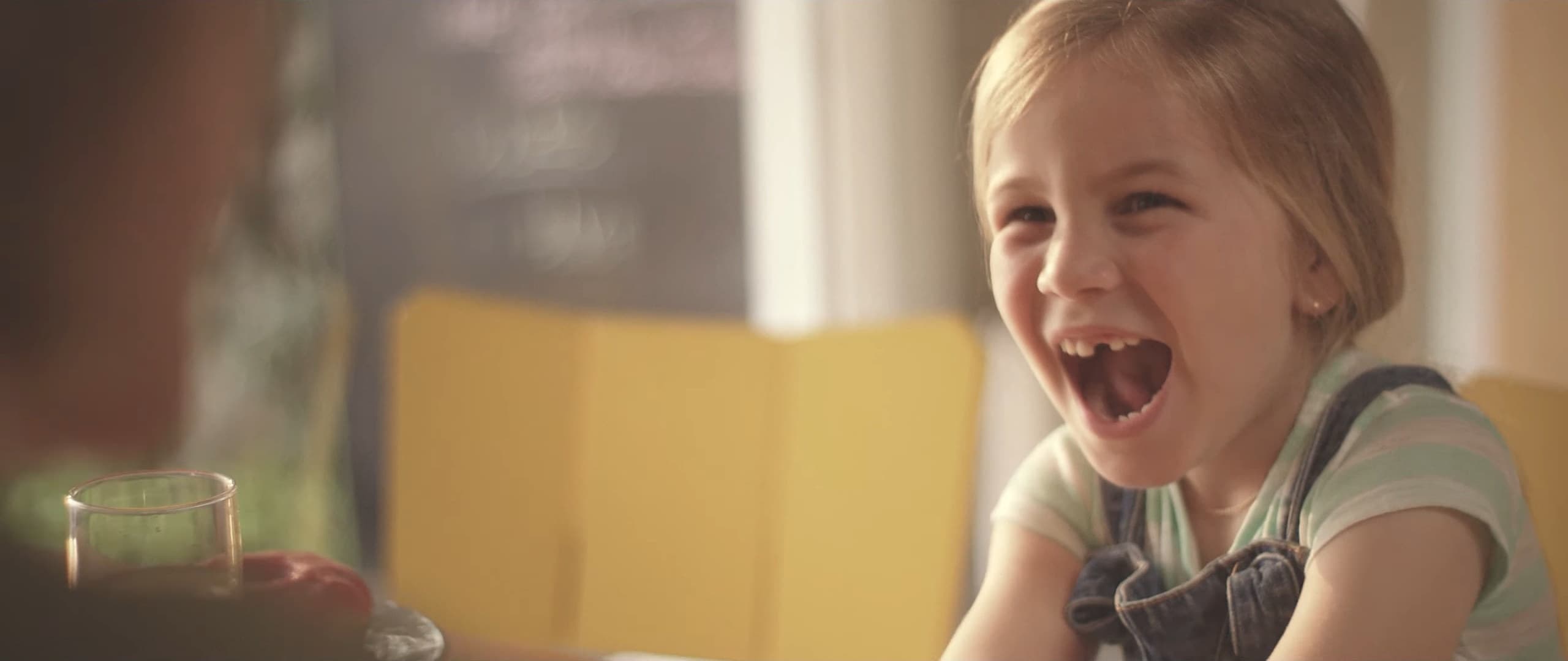A gap-toothed girl laughs with her mouth open