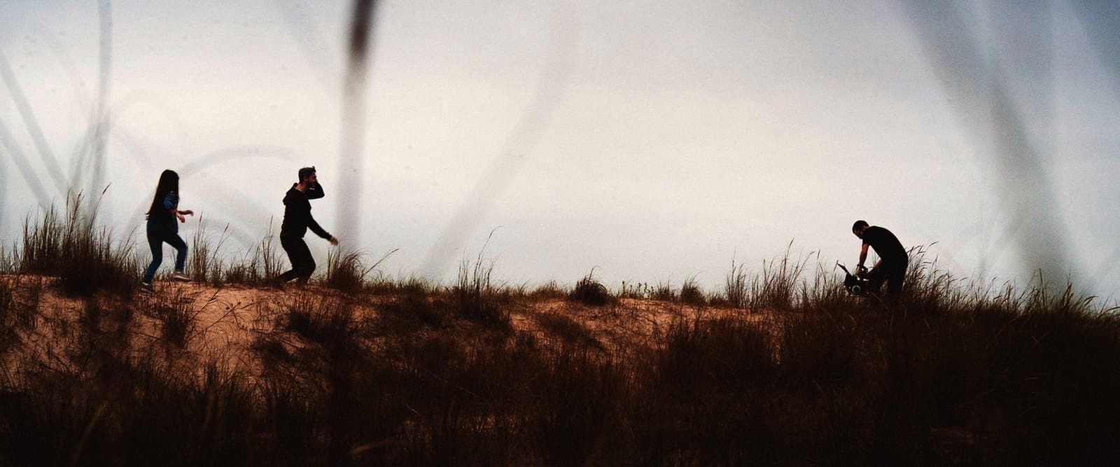 The crew films a scene on the dunes, the camera among the grass
