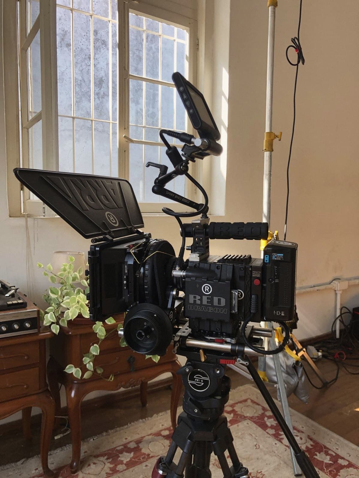 The RED camera set up on set, in a room with tall windows