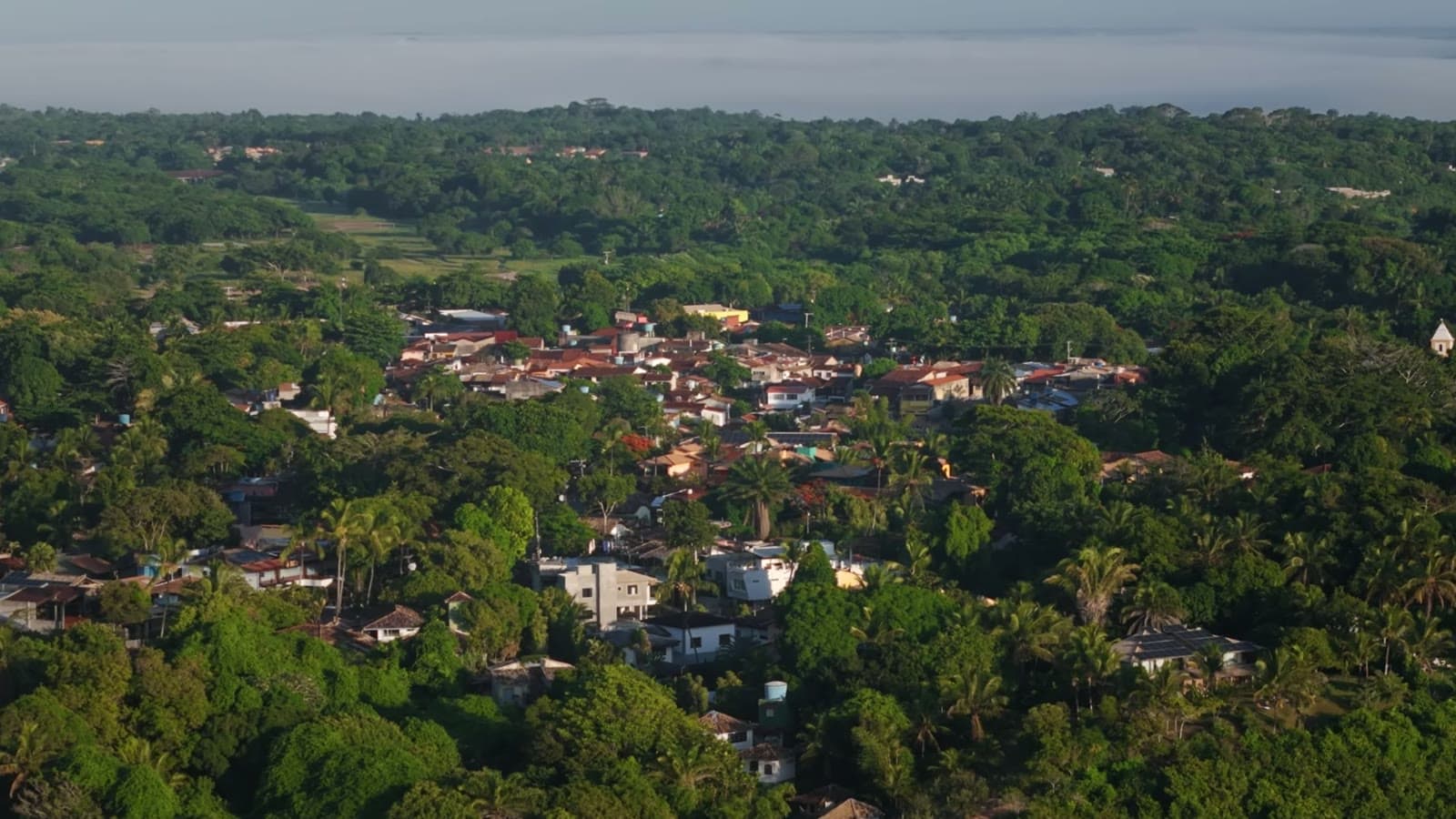 Aerial view of the center of Arraial da Ajuda, with the rooftops among the forest in the late afternoon