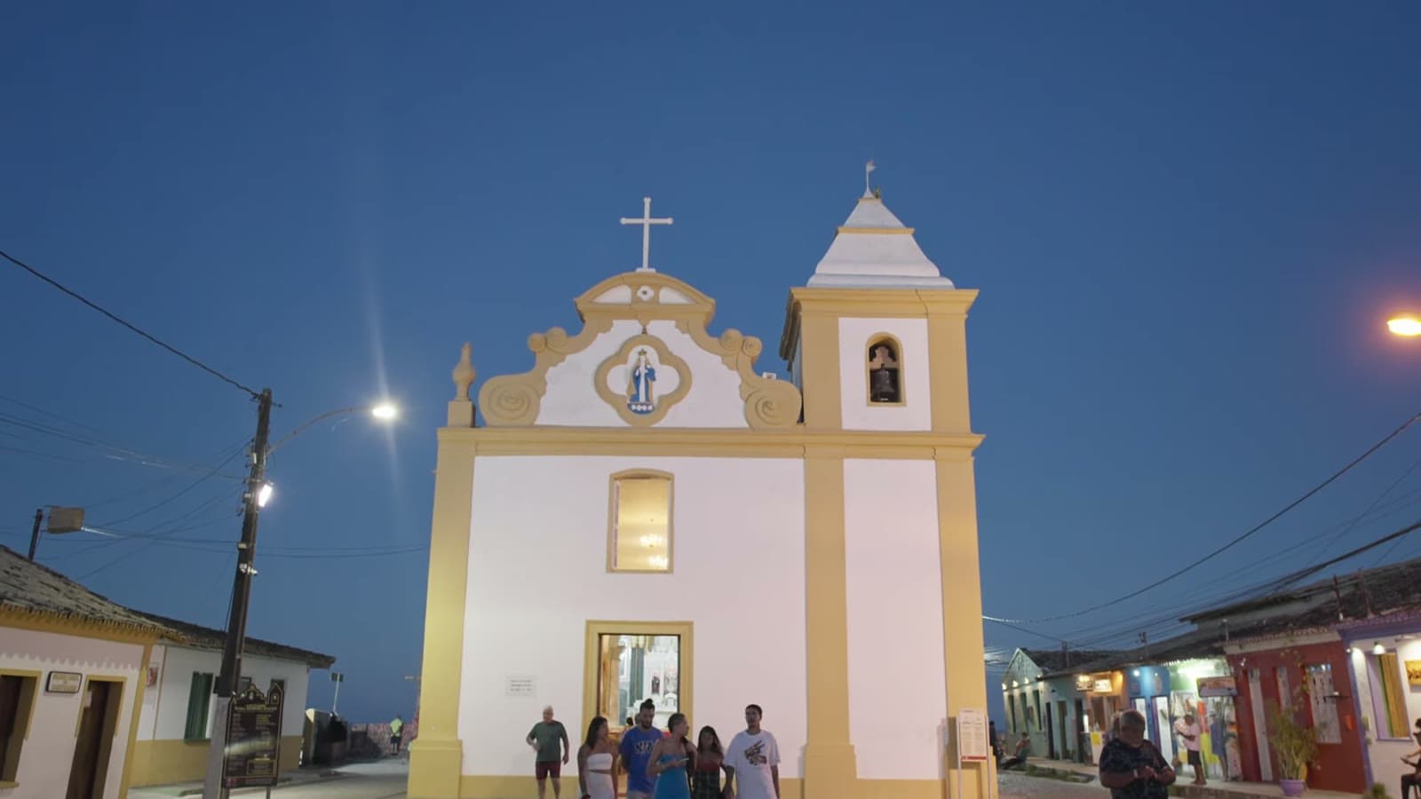 Igreja da Matriz in Arraial da Ajuda, white and yellow, in the early evening, with people in front