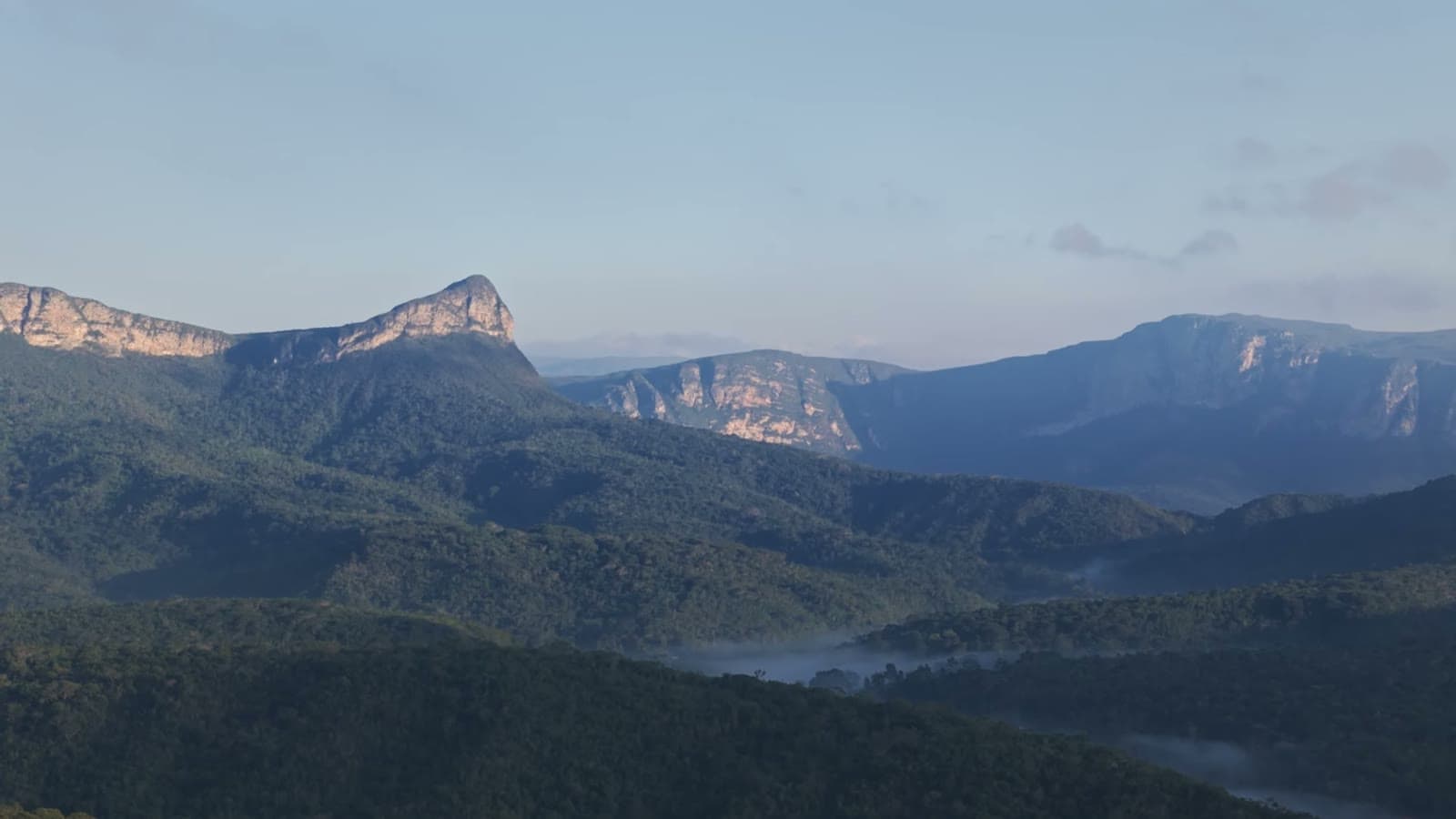 Pico do Gavião lit by the morning sun, above a valley covered in forest