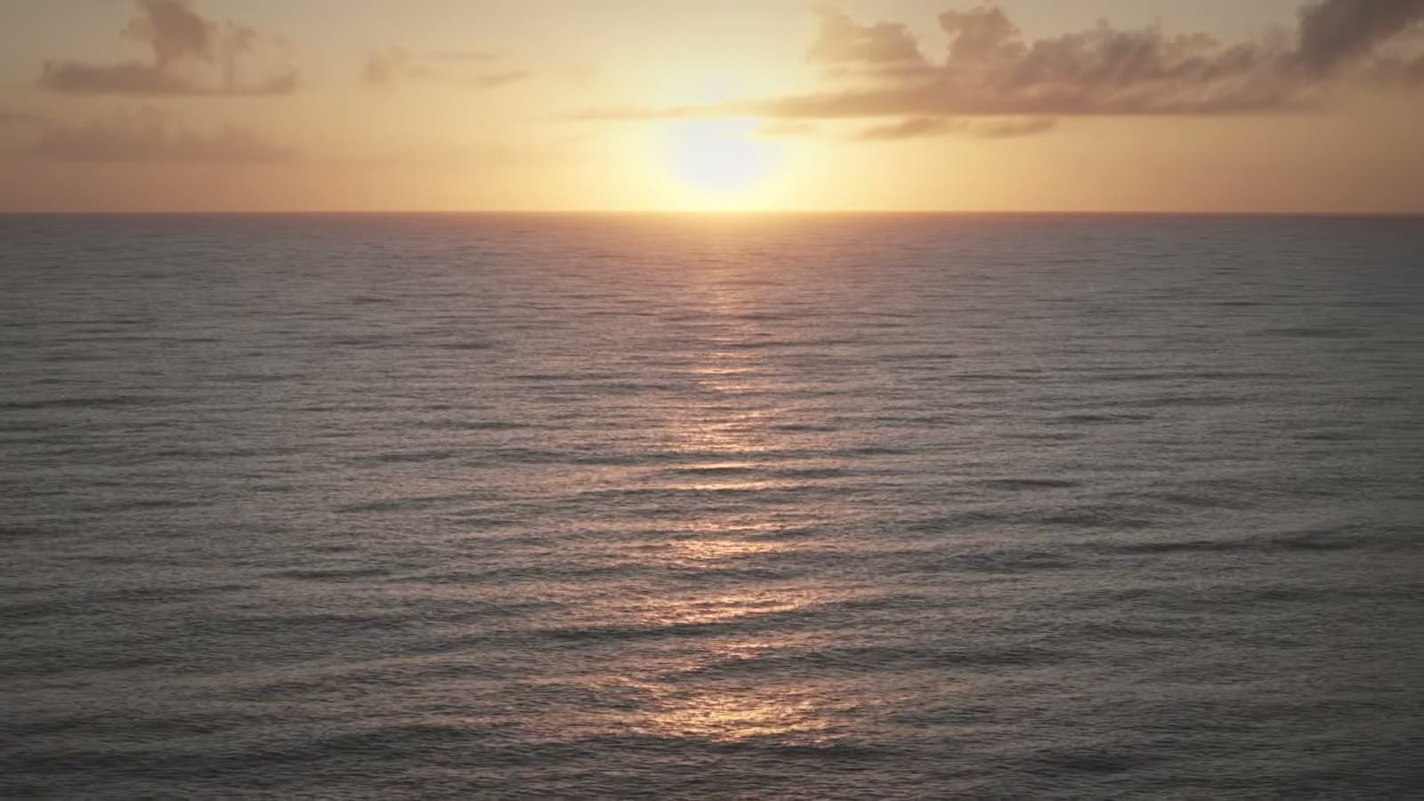 El sol saliendo en el horizonte, reflejado en el mar en calma