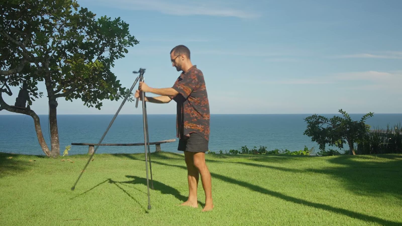 Nando montando o tripé de fibra de carbono num gramado, com o mar ao fundo
