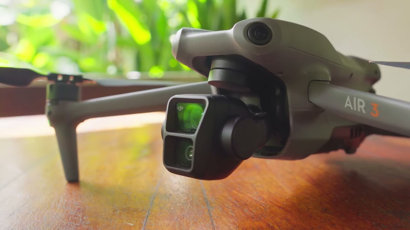 O drone DJI Air 3 pousado sobre a mesa de madeira, com as duas câmeras em destaque