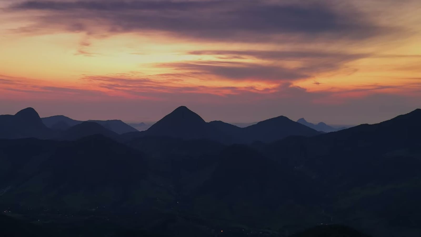 Orange and purple sunrise sky over a row of pointed mountains