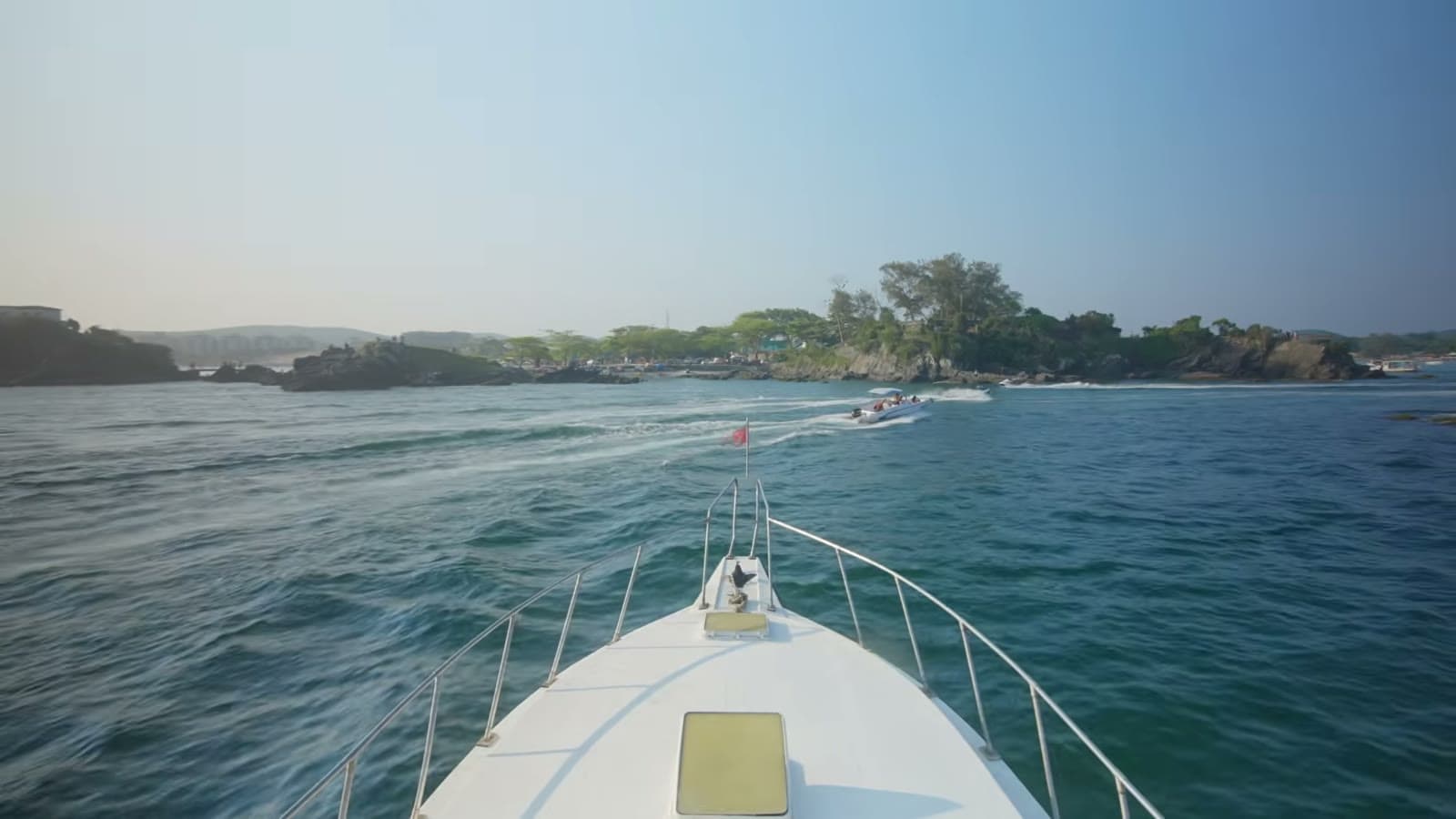 Bow of a dive boat heading toward an island covered in forest