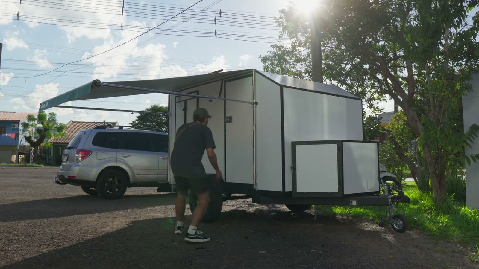 White mini trailer hitched to the silver Subaru Forester, with the low sun behind the trees
